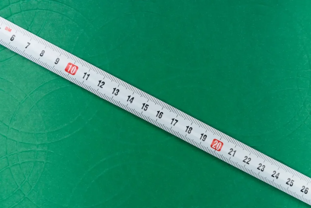 A tape measure laid across a green surface while measuring a space