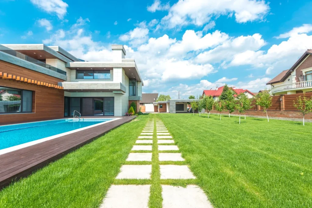Backyard swimming pool bordered by a manicured green lawn and stone path