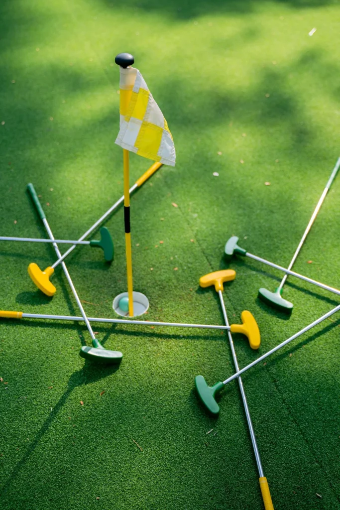 Synthetic backyard putting green with a flag in the hole and putters